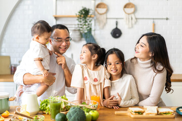 Portrait of happy love asian family father and mother with little asian girl daughter child having fun help cooking food healthy eat together with fresh vegetable salad and sandwich ingredient