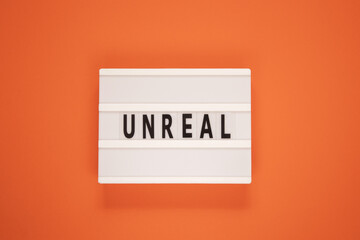 Word unreal from letters on orange background. Facts and figures true and lies concept