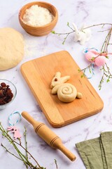 Step-by-step cooking of Easter Bunny Buns on a light background. Step two, forming a bun in the form of a rabbit