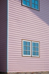 Sunlight and Shadow on surface of glass and wooden Windows on artificial wood Wall of Pastel pink Vintage House, Perspective side view and vertical frame 