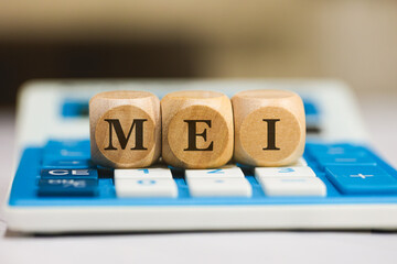A sigla MEI para Microempreendedor Individual escrita em dados de madeira que estão sobre uma...