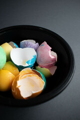 Coloured eggshells in a bowl on a dark background