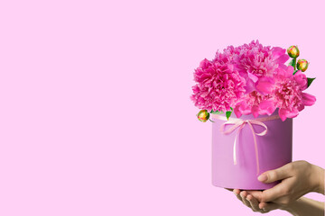 box with beautiful peonies in women's hands. isolated on a light background