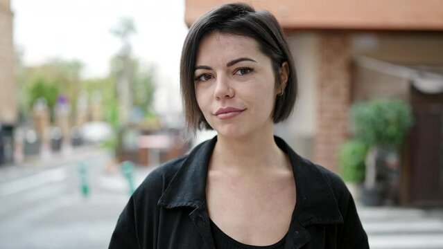Young caucasian woman standing with serious expression saying no with finger at street
