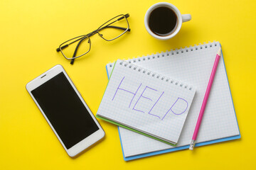 Notepad with the inscription help, coffee and a smartphone on a bright yellow background