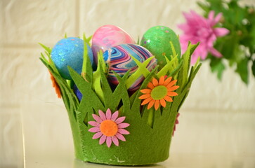 Colorful easter quail eggs in nest and tulips on pink background with . Flat lay. Spring composition. Happy easter greeting card. Copy space