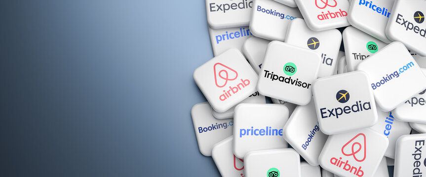 Logos of the travel related sites Expedia, priceline, booking.com, Airbnb and Tripadvisor on a heap on a table. Web banner format, copy space
