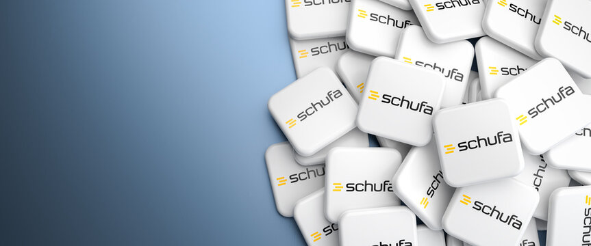 Logos of the German private credit bureau Schufa on a heap on a table. Web banner format, copy space