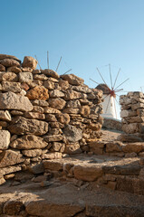 A rustic stone wall protects the famous windmills of the island of Mykonos, Greece. They have become tourist attractions and express the poetry of the Aegean wind blowing across the island.