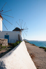 Vertical view of white windmills in the island of Mykonos against the blue sky. These historic and mills are a tourist destination for romantic and honeymoon couples