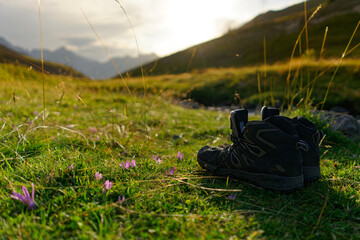 a pair of walking shoe on the grass at sunset. illustration of hiker's rest after a day of walking.