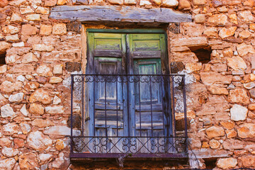 Very old green blue balcony. An ancient red brick house with cracked wooden balconies door, wrought metal railing. Old abandoned building exterior. Travel photography. Vintage details of architecture.