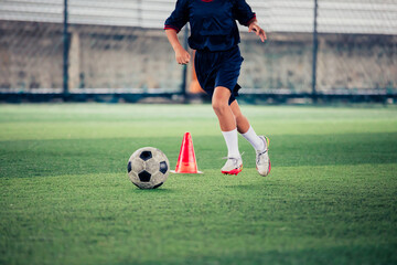 Children playing control soccer ball tactics cone on a grass field with for training background