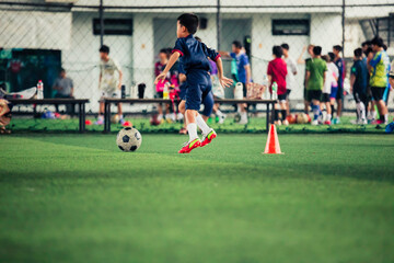 Children playing control soccer ball tactics cone on a grass field with for training background