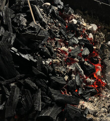 Black rough charcoal with some burning embers 