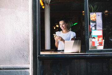 Portrait of cheerful female freelancer with laptop and smartphone devices smiling at camera,happy...