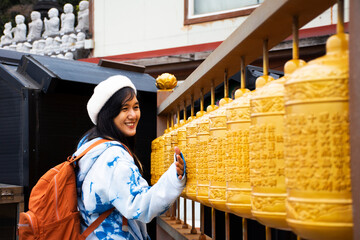 Traveler thai women travel visit and rite rotate spin with prayer wheels for praying blessing holy wish mystery in Sanbangsa Temple at Seogwipo city on February 18, 2023 in Jeju do island, South Korea