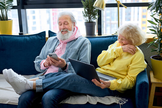 Happy mature retired couple using laptop and smartphone, reading news or watching tv series online. aged caucasian people communicating in social network, old people and modern tech concept