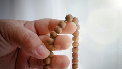 Muslim woman praying with wooden prayer beads. Islamic concept.