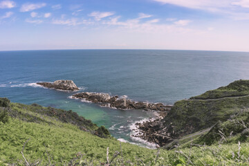 Spectacular views of the turquoise sea above a mountain with green vegetation on a summer day in Galicia. Spain