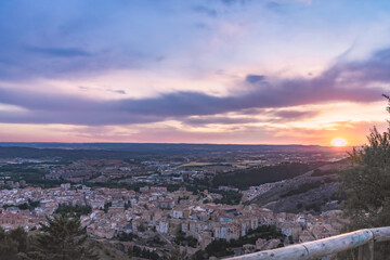 Fototapeta na wymiar Sunset in the town of Cuenca, with clouds of different colors and the sun hiding on the horizon. Cuenca, Spain