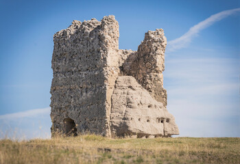 Ruins of the wall of the castle of Turegano in Segovia in the middle of the dry and yellow field in summer. Segovia. Spain