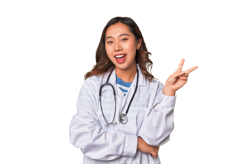 A young asian doctor woman joyful and carefree showing a peace symbol with fingers.