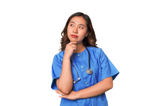 A young nurse chinese woman looking sideways with doubtful and skeptical expression.