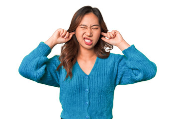 A young chinese woman covering ears with fingers, stressed and desperate by a loudly ambient.