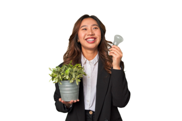 A young Chinese businesswoman holds a lightbulb and plant, embodying her innovative ideas and commitment to sustainability and the environment.