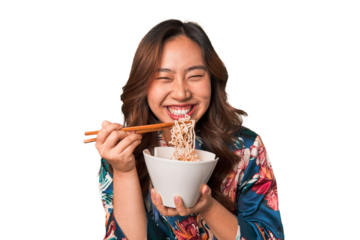 Happy young Asian woman eating noodles with chopsticks.