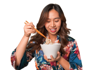 Happy young Asian woman eating noodles with chopsticks.