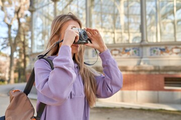 Young caucasian woman captures artistic beauty of the crystal palace in Madrid with her camera.