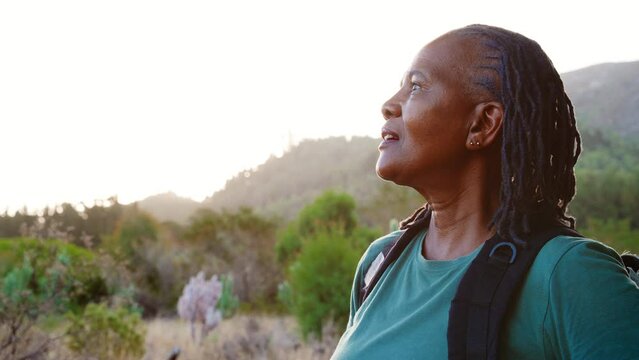 Close up head and shoulders portrait of senior man with backpack enjoying hiking through countryside with copy space- shot in slow motion