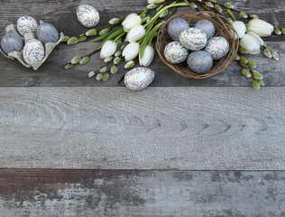 Ostereier mit weißen Tulpen und Zweigen von Weidenkätzchen auf einem hölzernen Hintergrund mit...