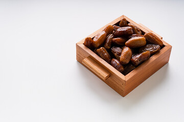 Dried dates fruit in wooden tray isolated on white background. 
