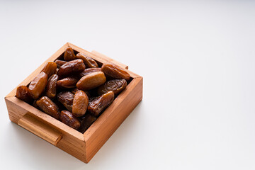 Dried dates fruit in wooden tray isolated on white background. 
