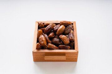 Dried dates fruit in wooden tray isolated on white background. 
