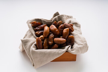 Dried dates fruit in wooden tray with soft napkin isolated on white background. 
