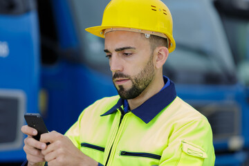 man with smartphone in front of heavy vehicle