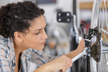 beautiful woman tightening bicycle wheel screws in the garage