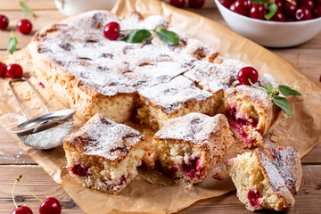 Sponge cake or chiffon cake with cherries, so soft and delicious with ingredients on wooden table. Homemade bakery concept for background and wallpaper.