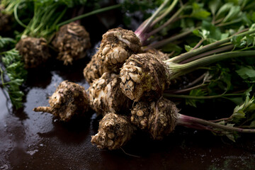 Washed celery tubers in close-up with cut roots and green leaves on a wet background. Background. Selective focus
