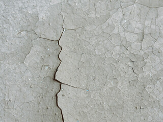 Peeling paint on the wall. Old concrete wall with cracked flaking paint. Weathered rough painted surface with patterns of cracks and peeling. Grunge texture for background and design. Closeup