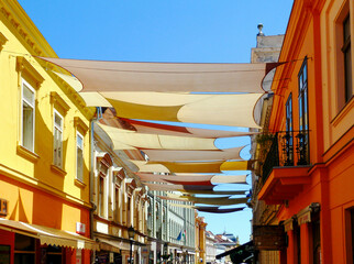 street awnings in perspective. colorful canvas sail shade and UV protection fabric suspended from...