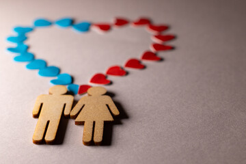 Male and female love LGBT. In marriage, family icons. Couple of lovers. A woman and a man are holding hands. Wooden people with paper blue and red hearts