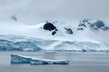 Iceberg with stunning mountainous backdrop of Wilhelmina Bay in Antarctica