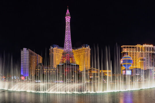 Las Vegas, United States - November 23, 2022: A picture of the Bellagio Fountain Water Show at night, with the Eiffel Tower of the Paris Las Vegas behind it.