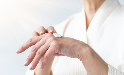 Obraz na płótnie Canvas Woman smears cream on her hand, close-up