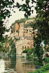 Fototapeta na wymiar Village on the river banks with out of focus trees in front